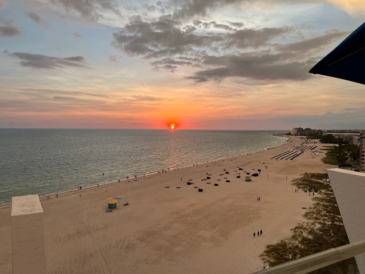 Sunset over the Gulf of Mexico from a St. Petersburg beach, with calm water, wide sand, and pastel sky.
